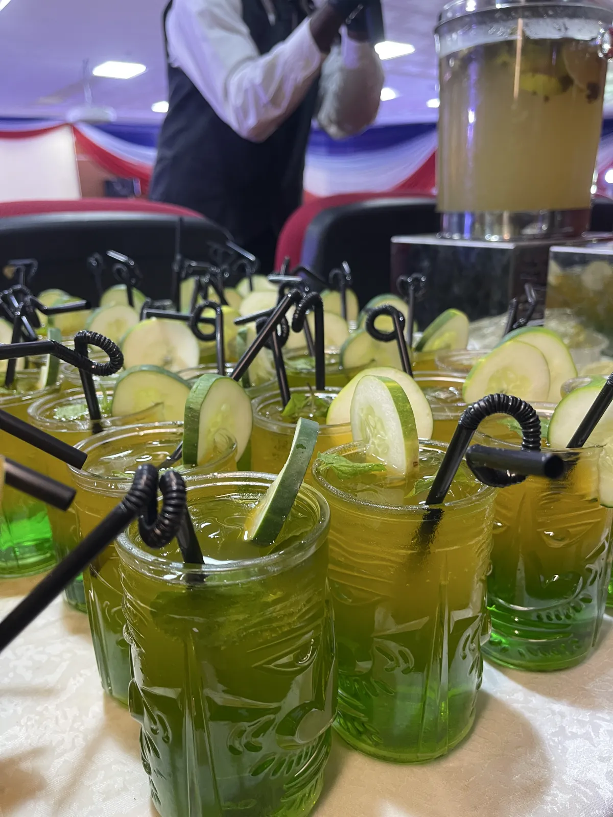 Cucumber and mint drinks in patterned glass mugs at an event beverage display