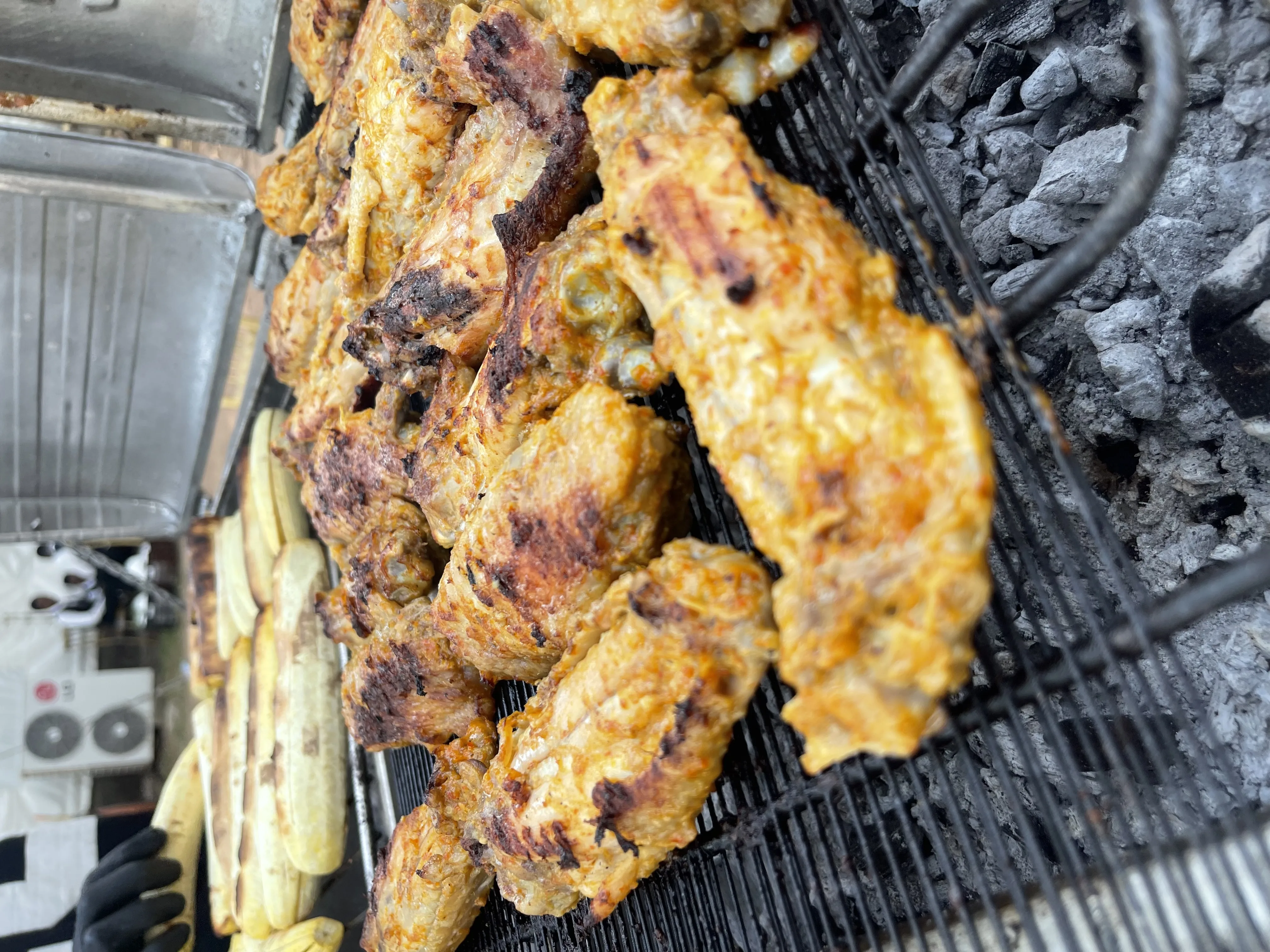 Chicken pieces grilling on open charcoal grill