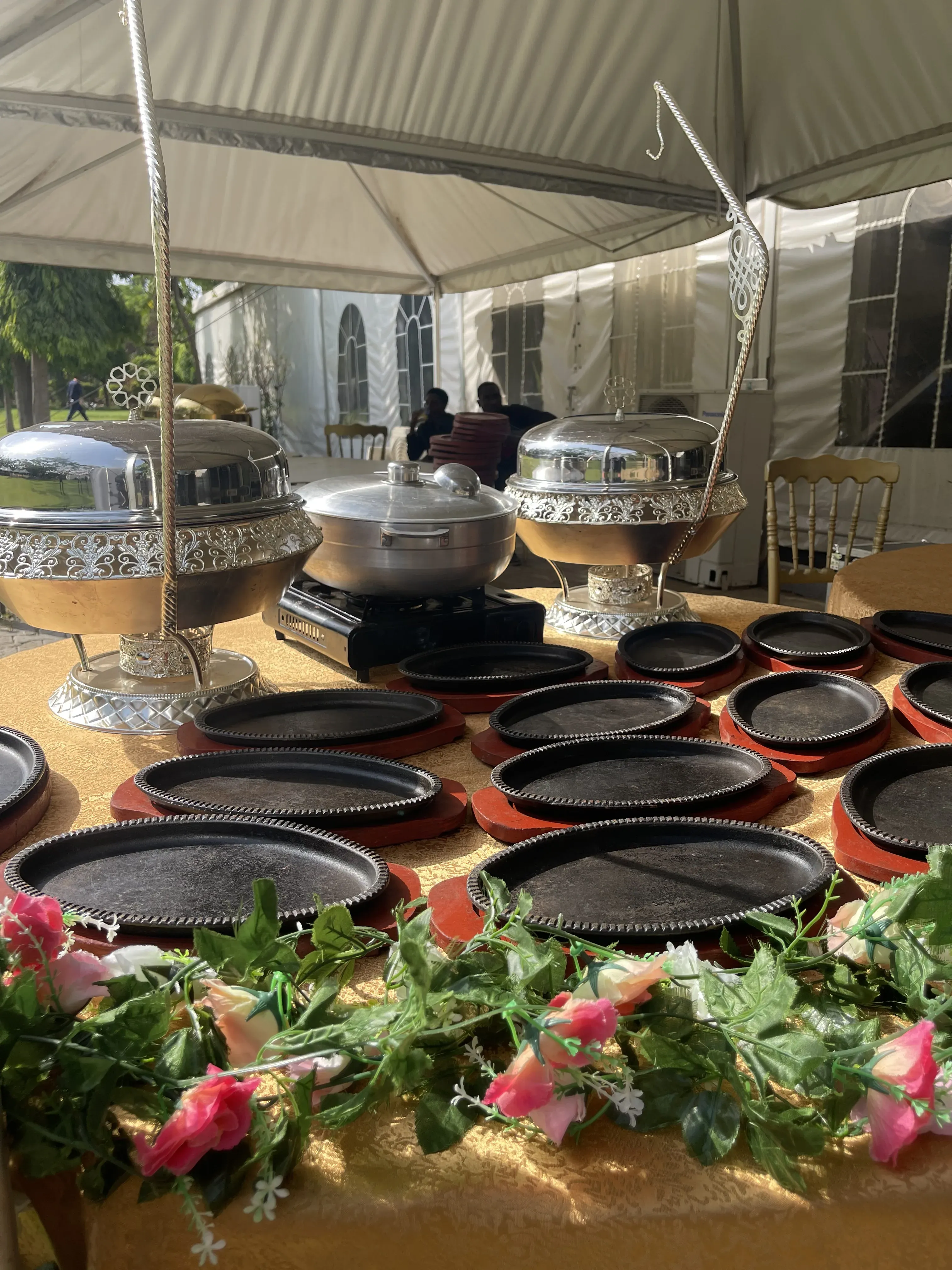 Outdoor event buffet with silver chafing dishes and floral decor