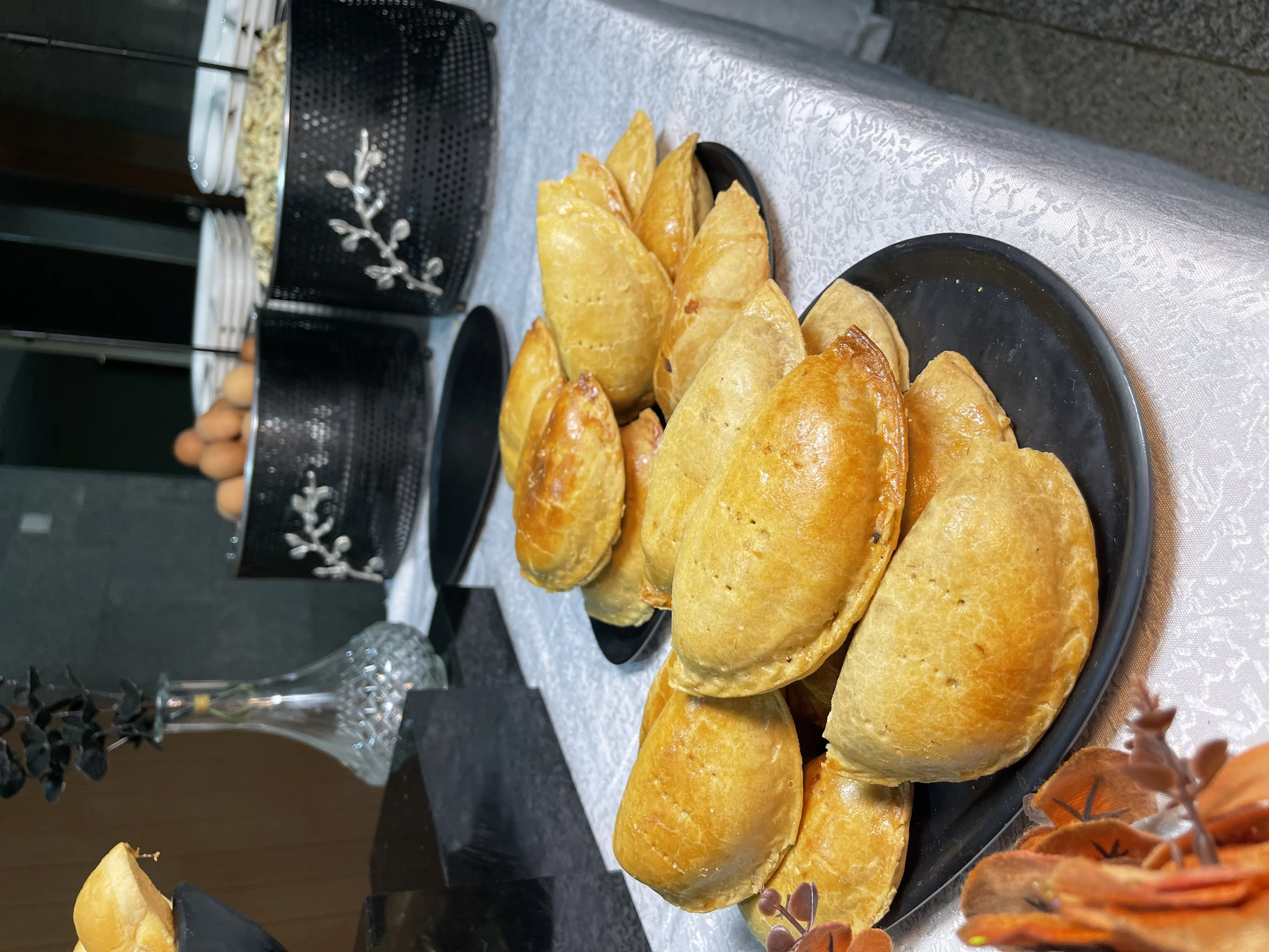 Golden meat pies arranged on a dark plate at a catering display