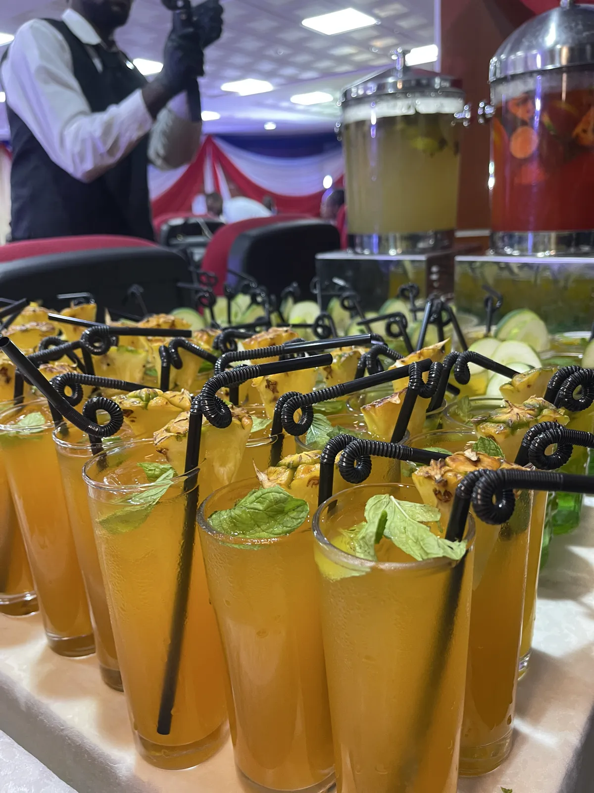 Tall glasses of pineapple mocktails garnished with mint at an event beverage table